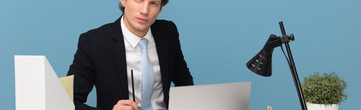 Man Sitting WIth Laptop computer on desk with lamp