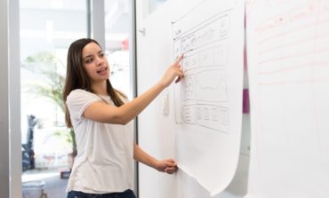 Women Wearing a white shirt standing beside a white board pointing at the board